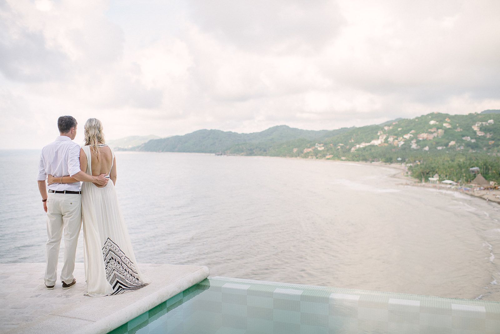 A couple at the edge of an infinity pool above the bay in Sayulita, Mexico