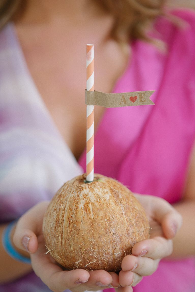 Hands holding a coconut with a striped paper straw
