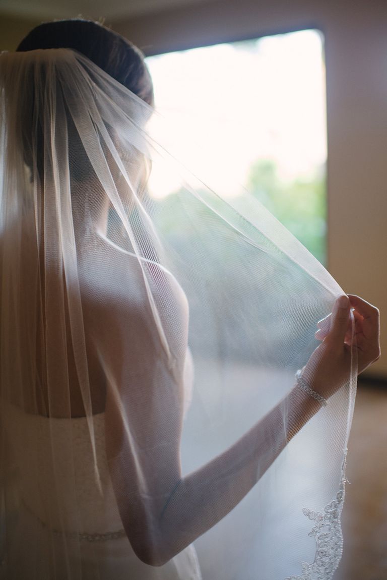 A bride lifting her veil in window light