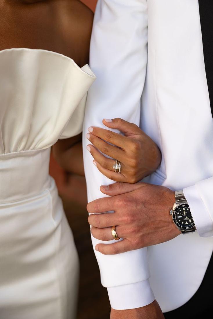 A couple’s hands, arm in arm, rings visible