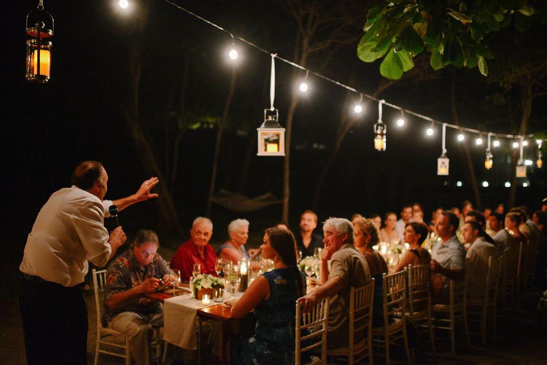 A guest giving a toast at a candlelit dinner