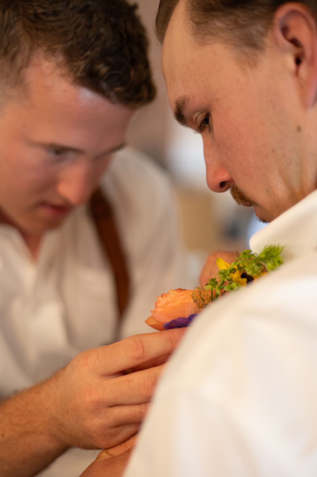 A groomsman pinning a boutonniere