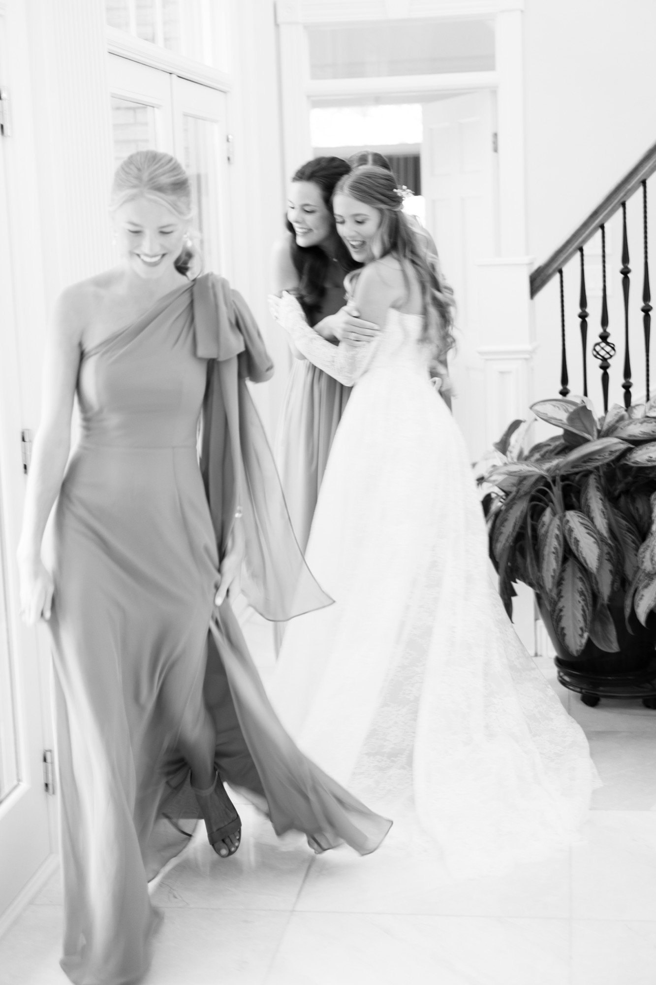 A bridesmaid helping the bride in a doorway, in black and white