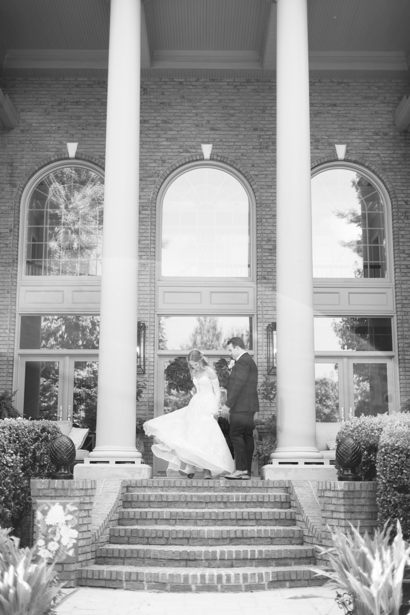 The couple under the columns of the brick house, in black and white