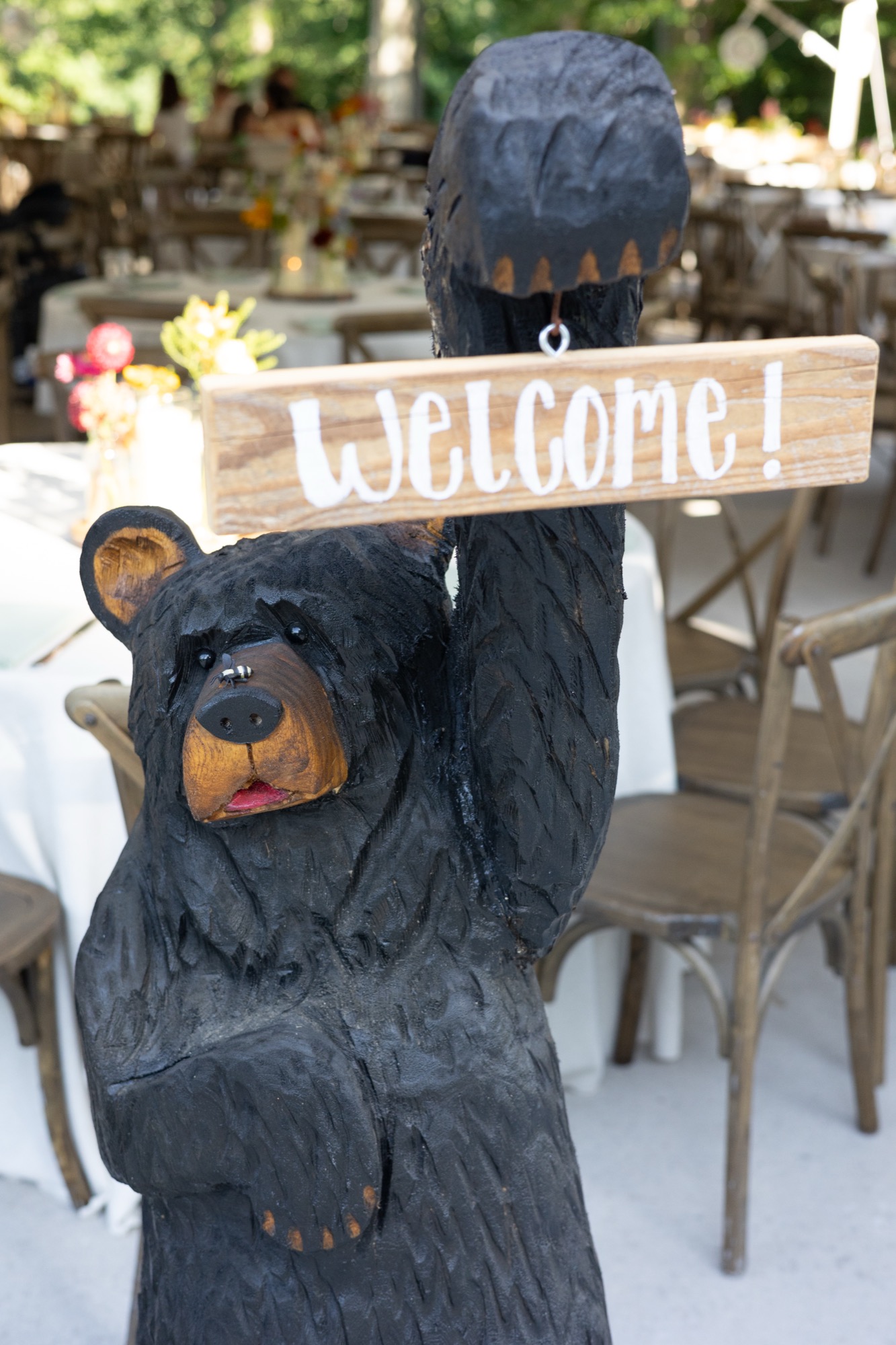 A carved bear holding a welcome sign