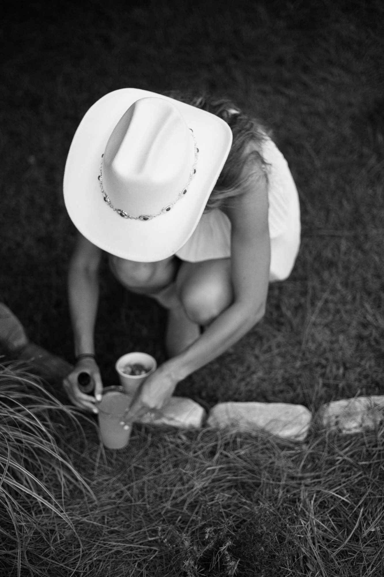 A guest in a cowboy hat pulling on her boots, in black and white