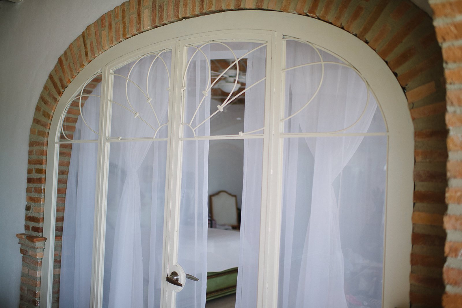 An arched window with white curtains
