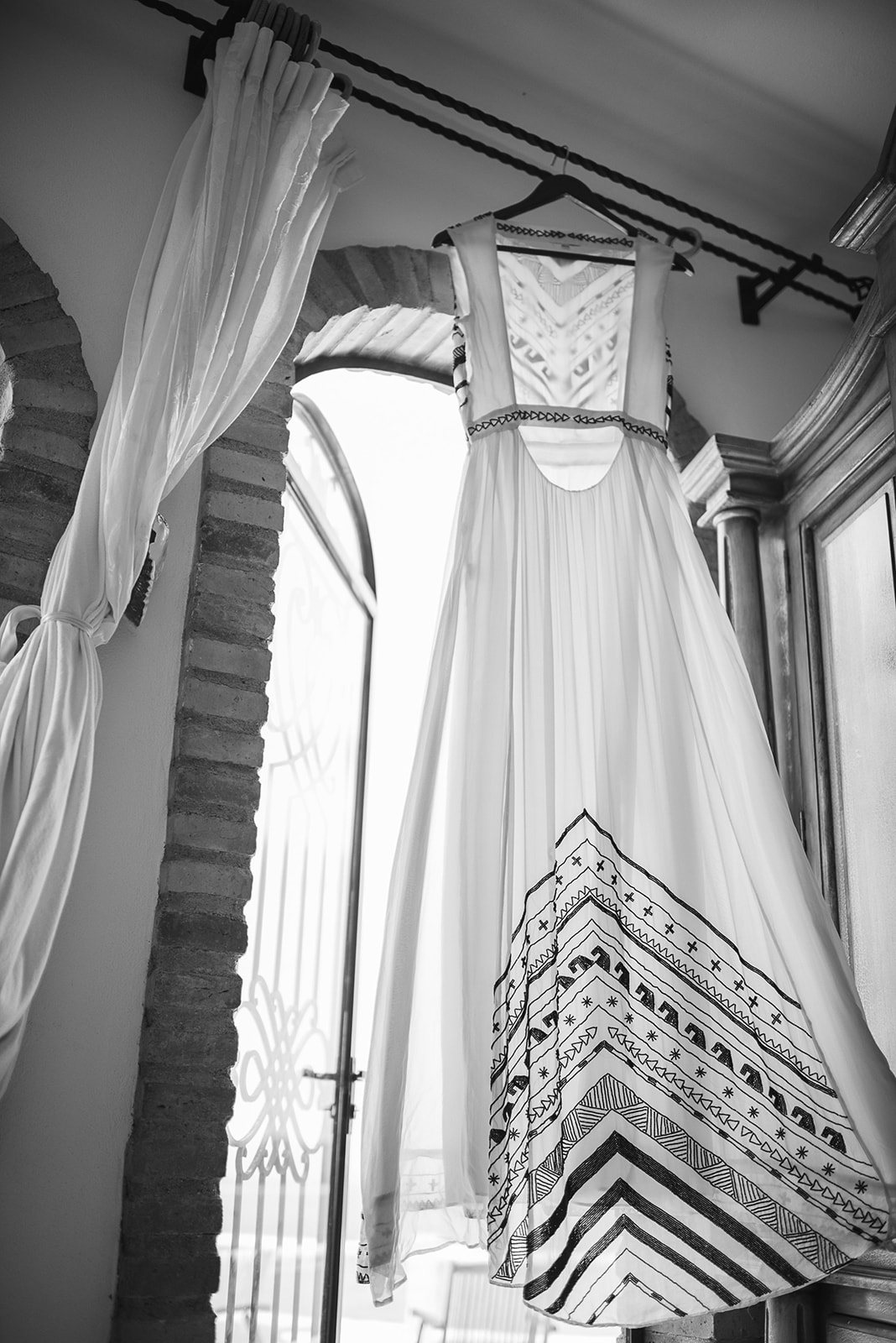 The gown hanging in a doorway, in black and white
