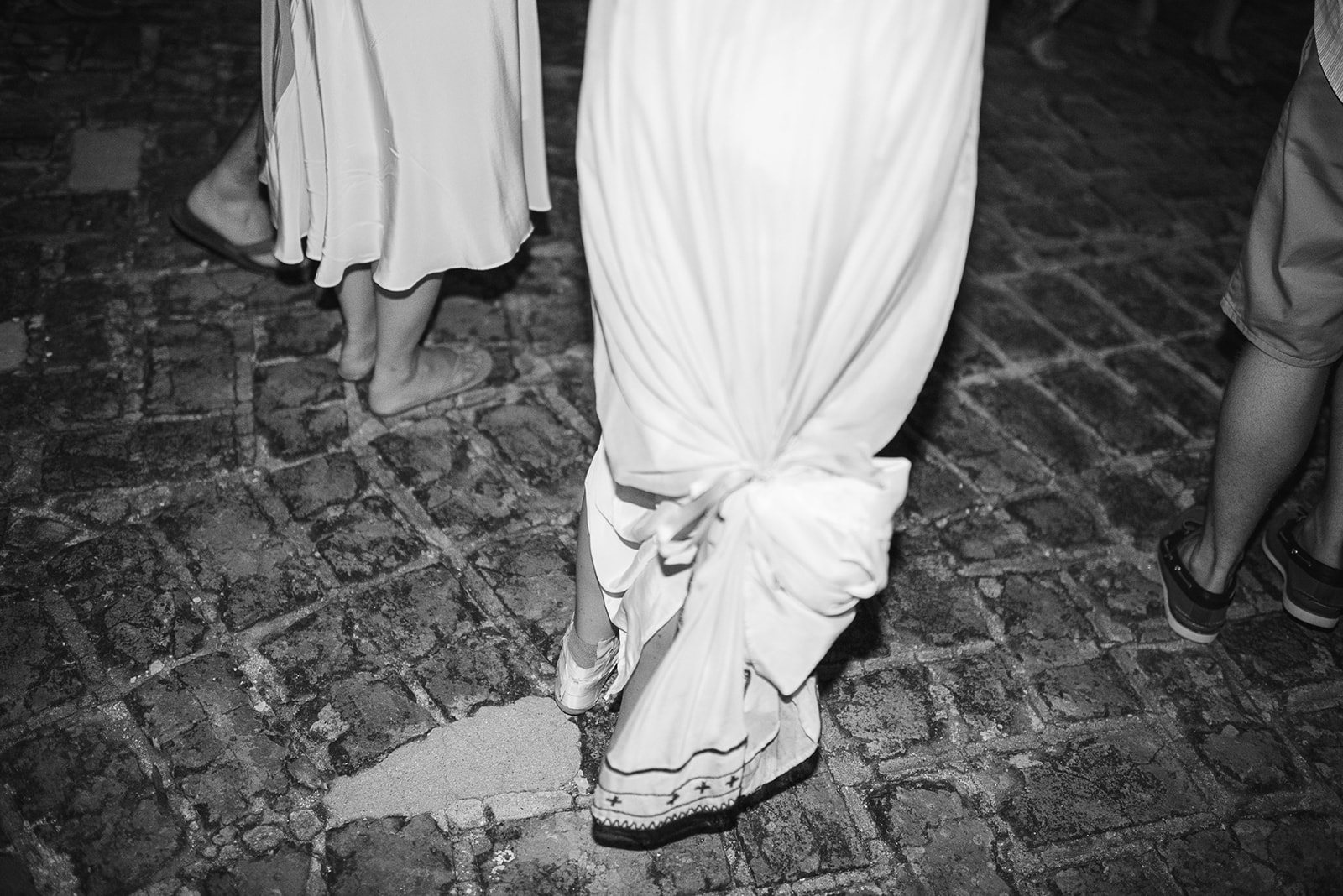The hem of the gown on the brick floor, in black and white