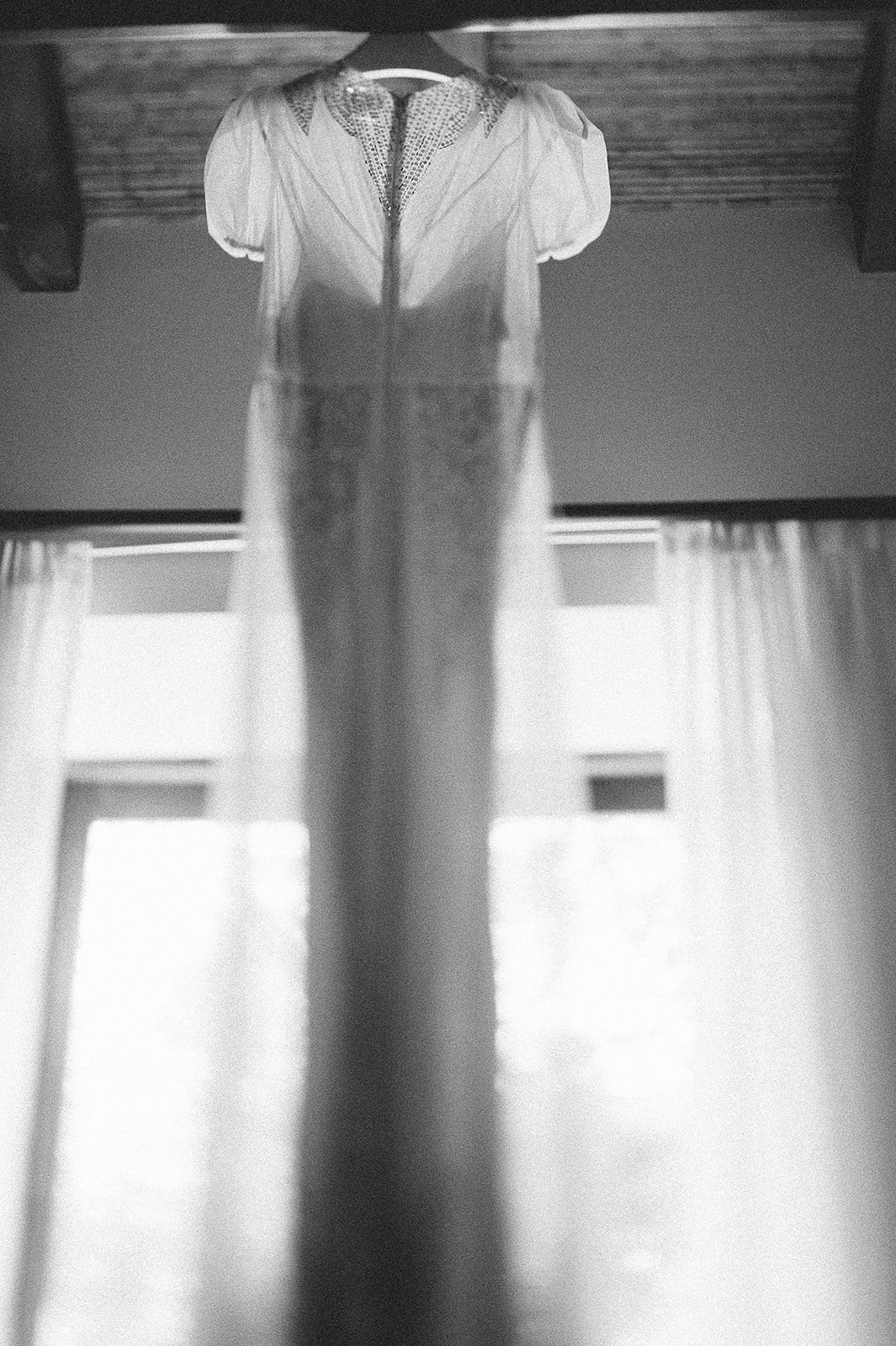 The gown hanging in the window light, in black and white