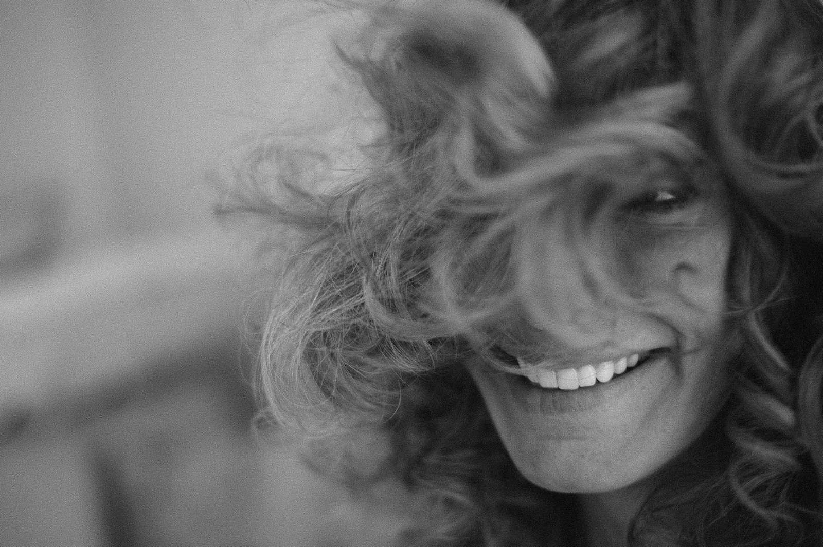 The bride laughing, hair across her face, in black and white