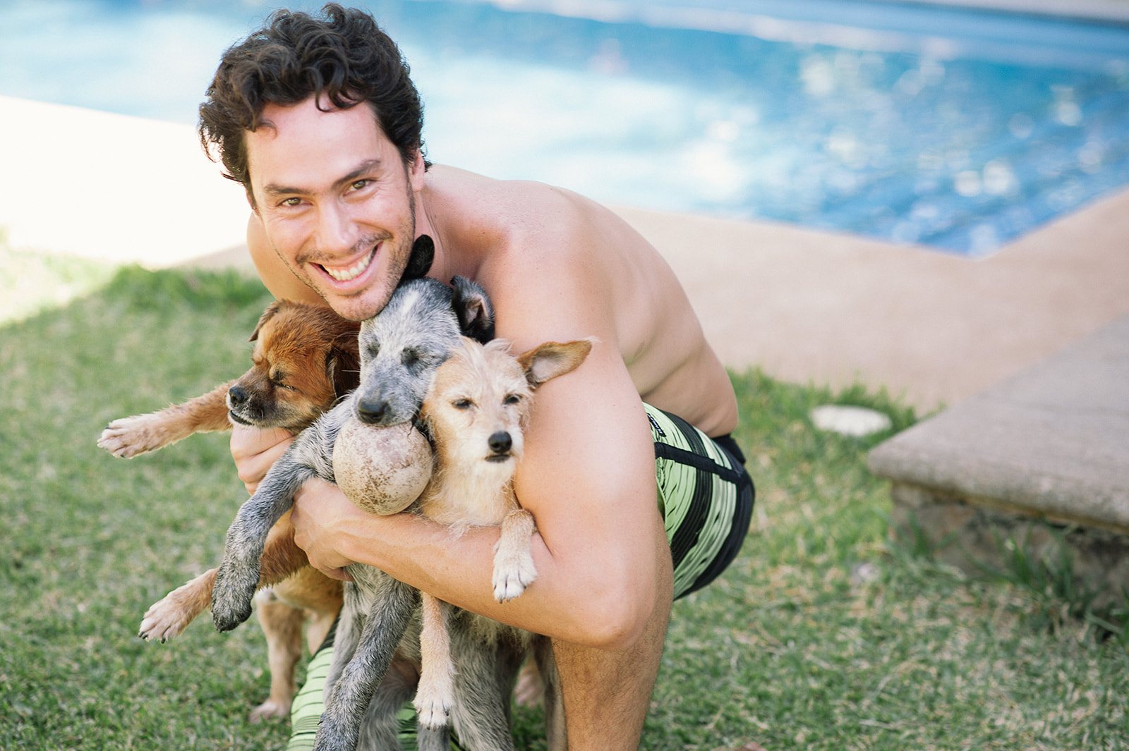 A friend hugging three small dogs by the pool
