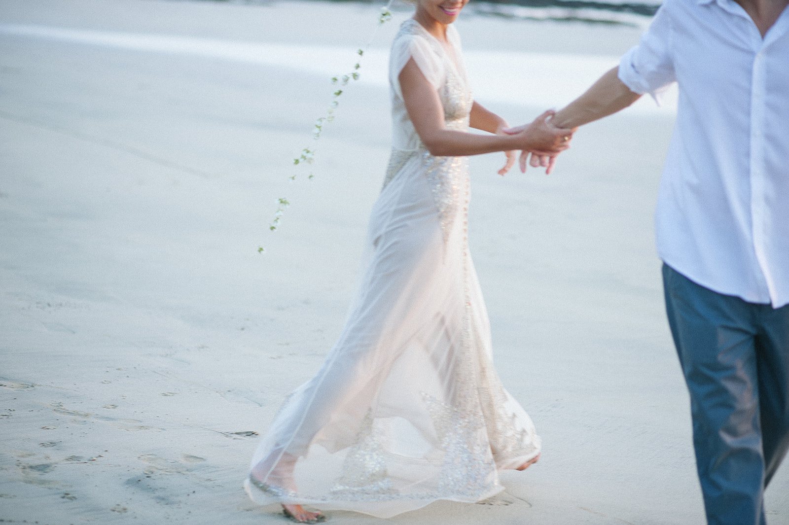 The couple walking hand in hand at the water's edge