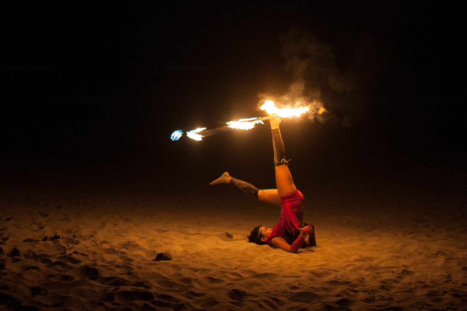 A fire dancer arched over the sand