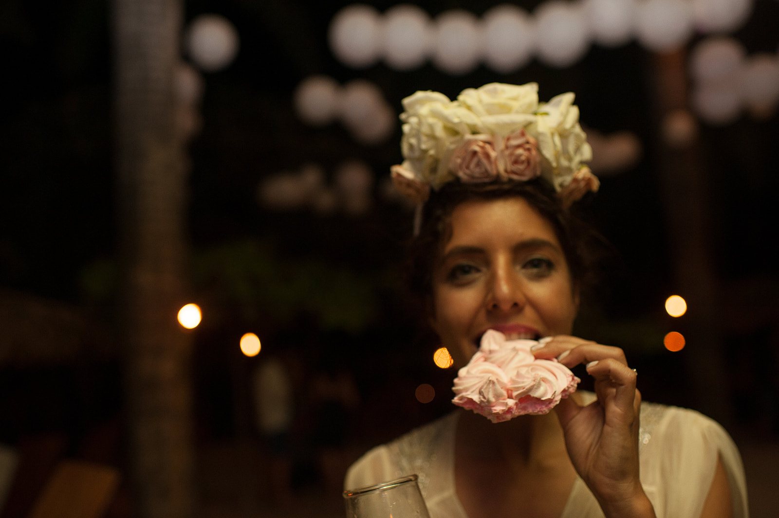 A guest in a flower crown with a mouthful of cake