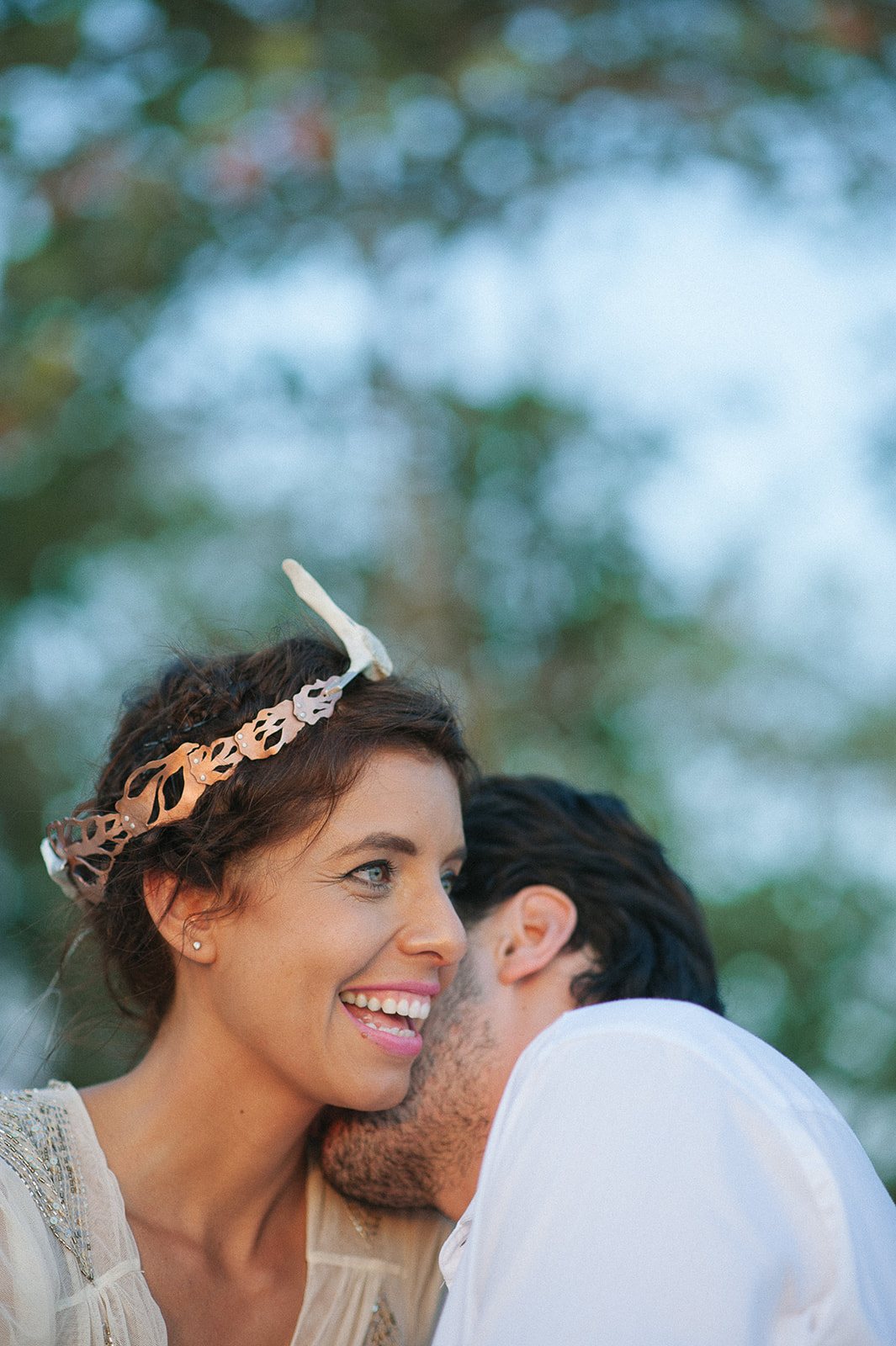 Carla laughing as Sebastian tucks into her cheek on the beach