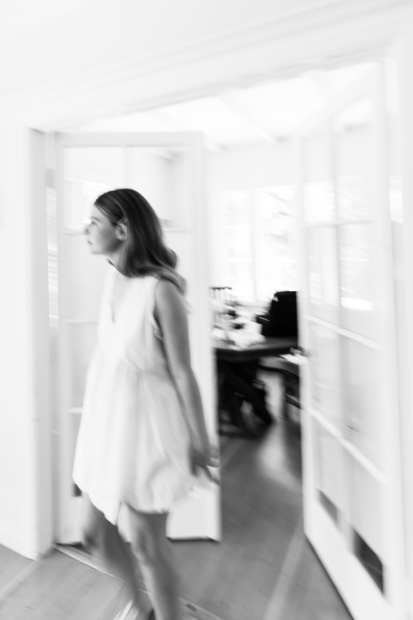 The bride walking through a sunlit room before getting dressed, in black and white