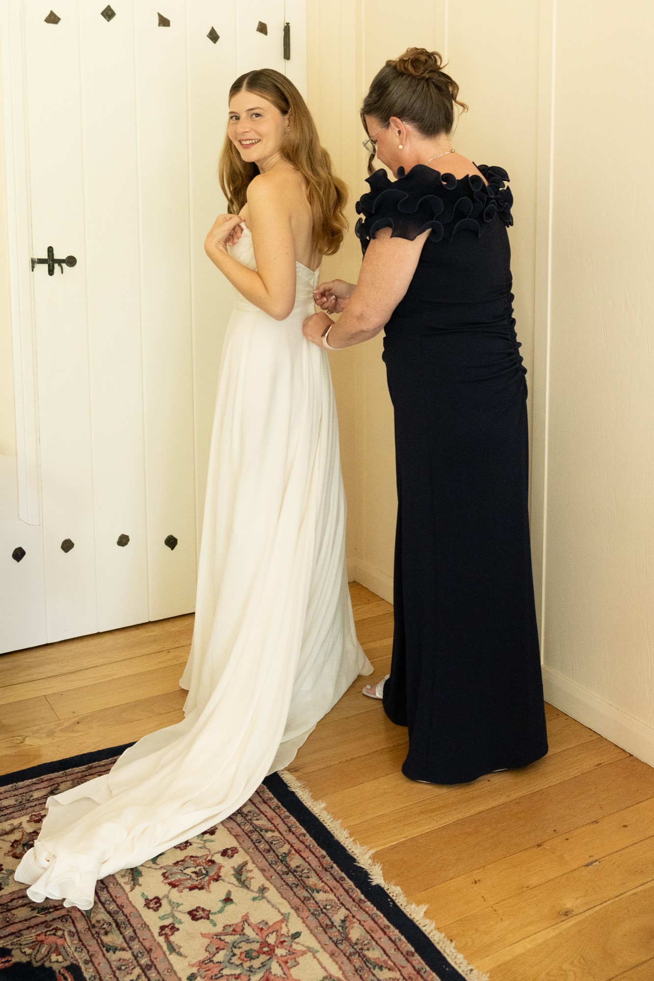 Her mother fastening the back of the gown