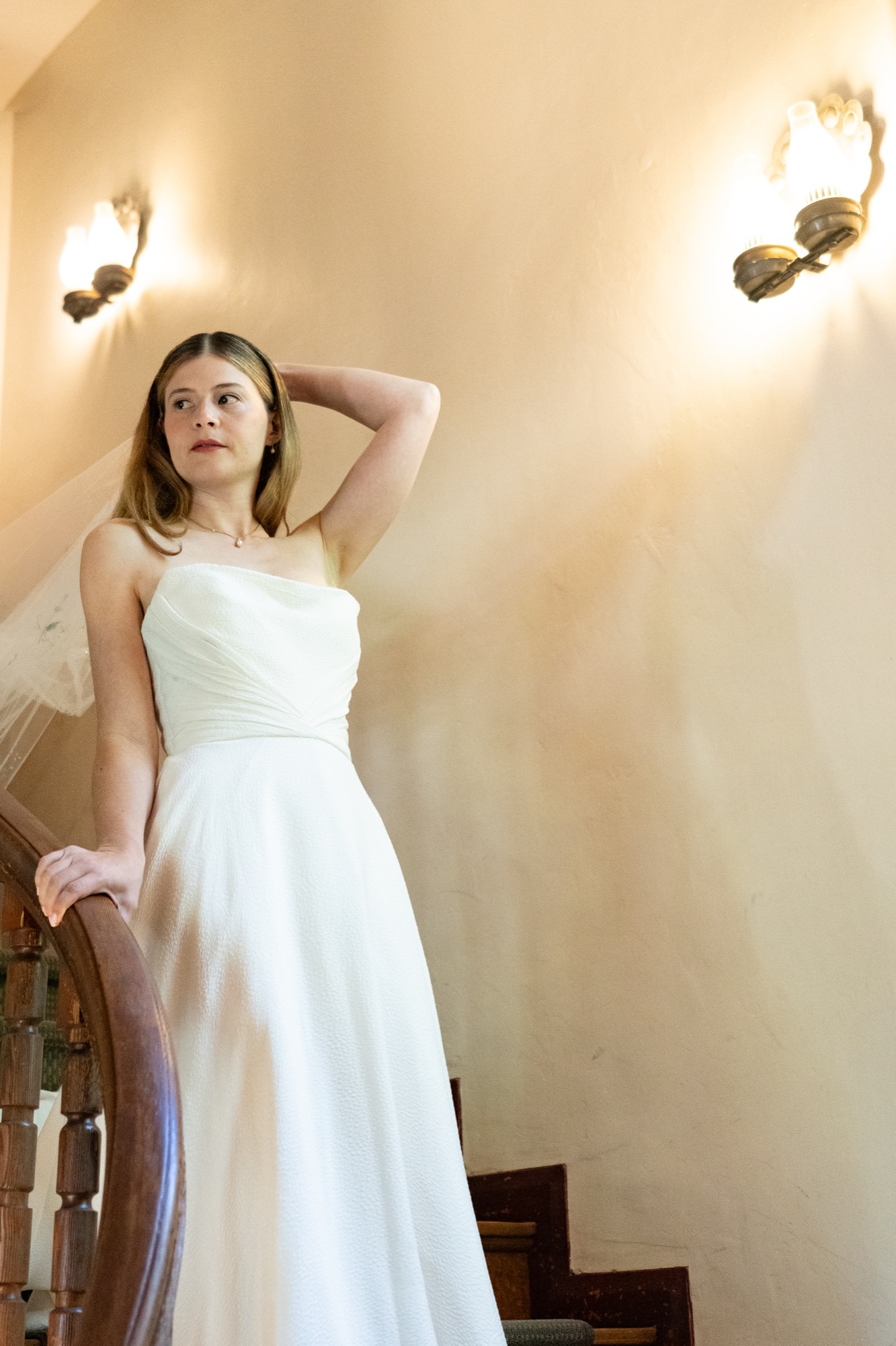 The bride on the stairs, one hand in her hair