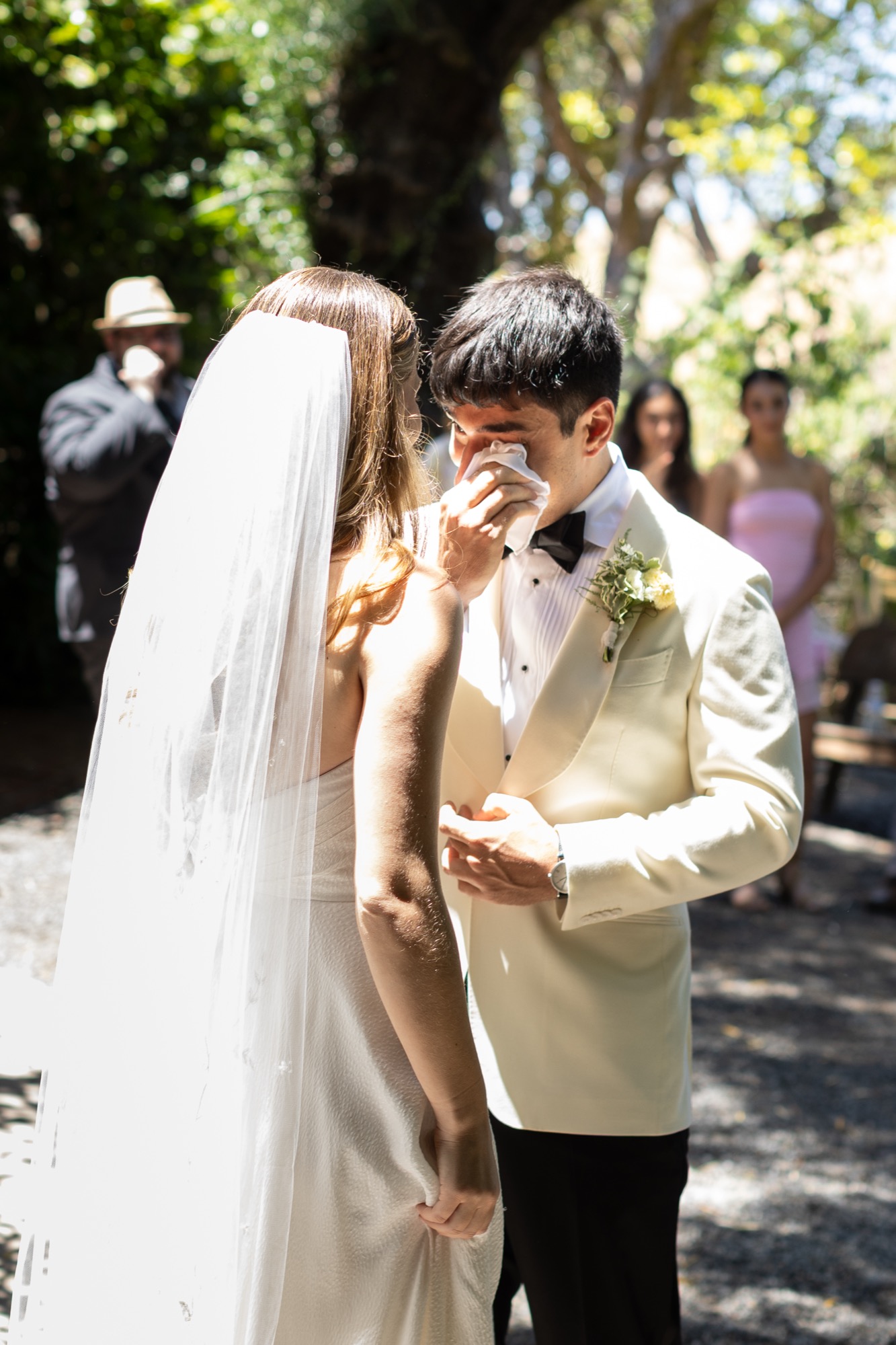 The groom wiping away a tear as he sees the bride