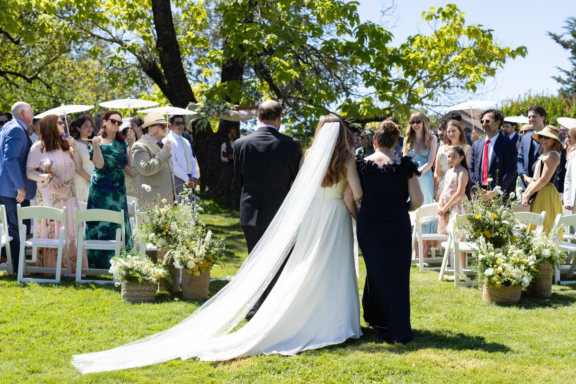 The bride crossing the lawn to the ceremony, train behind her
