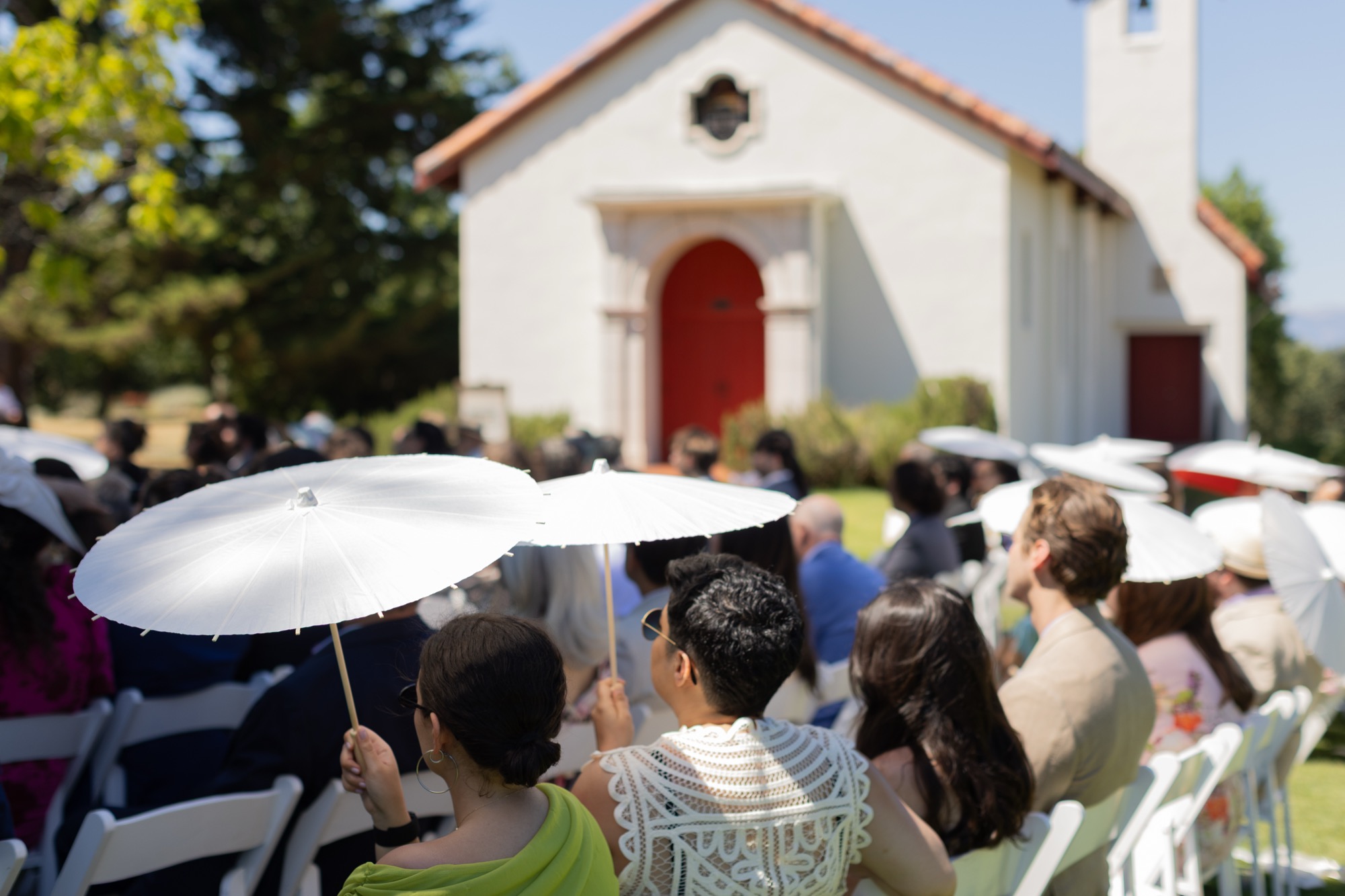 Guests under white parasols outside a chapel at Bishop’s Ranch
