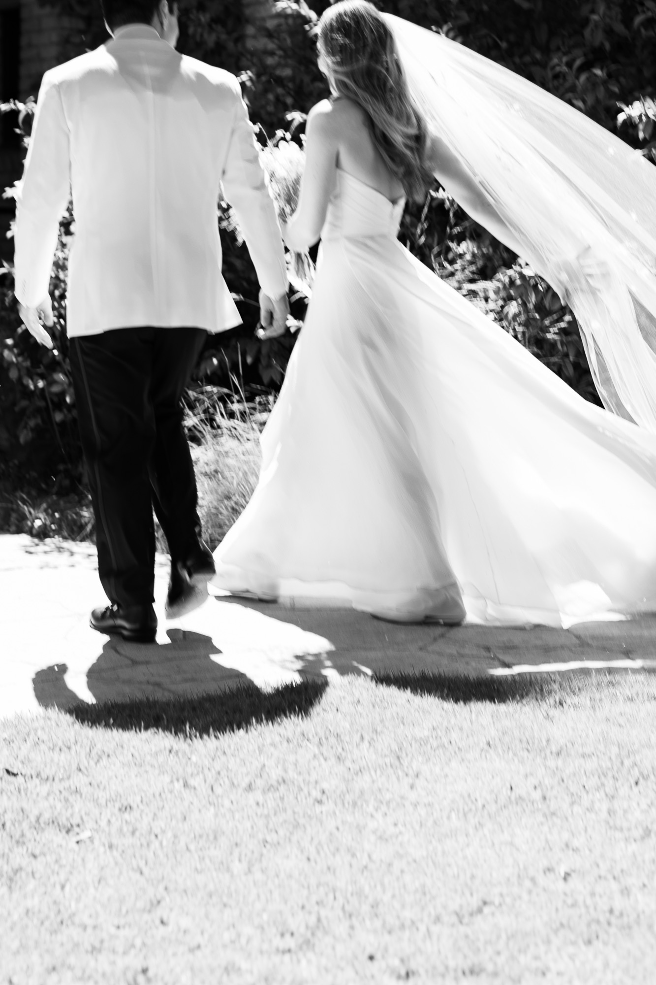 The couple walking back up the aisle, veil flying, in black and white