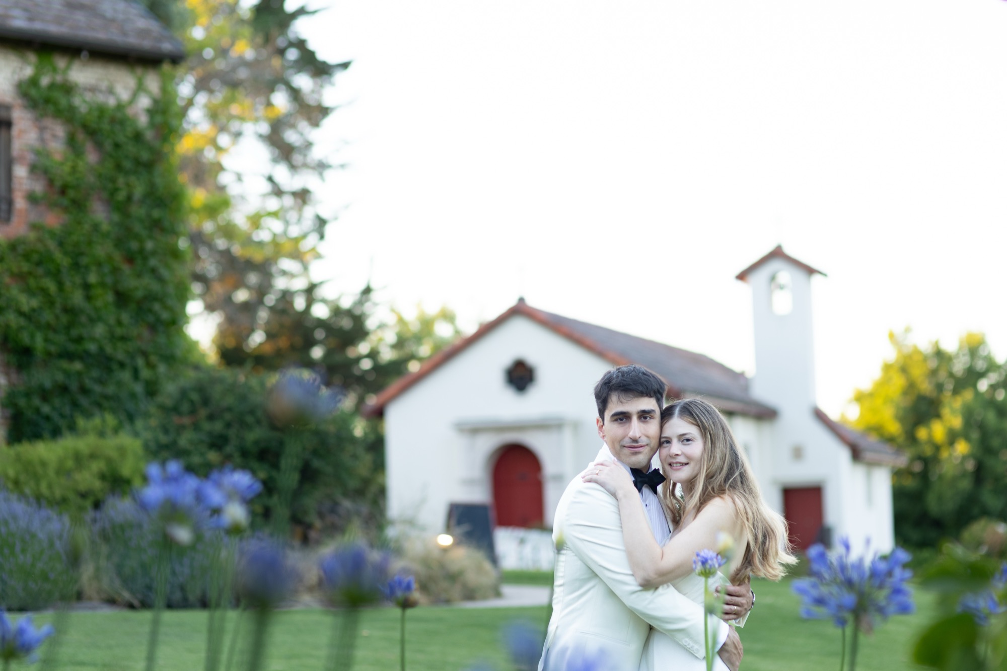 A couple beside a white chapel among blue flowers