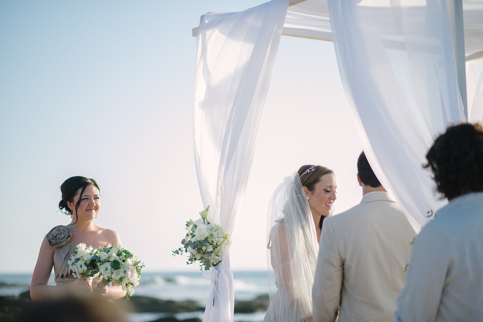 The ceremony under white drapes on the beach