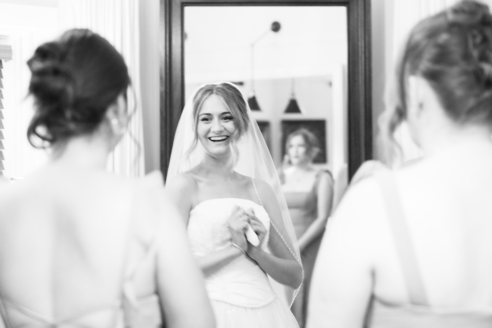 The bride laughing with her bridesmaids, in black and white