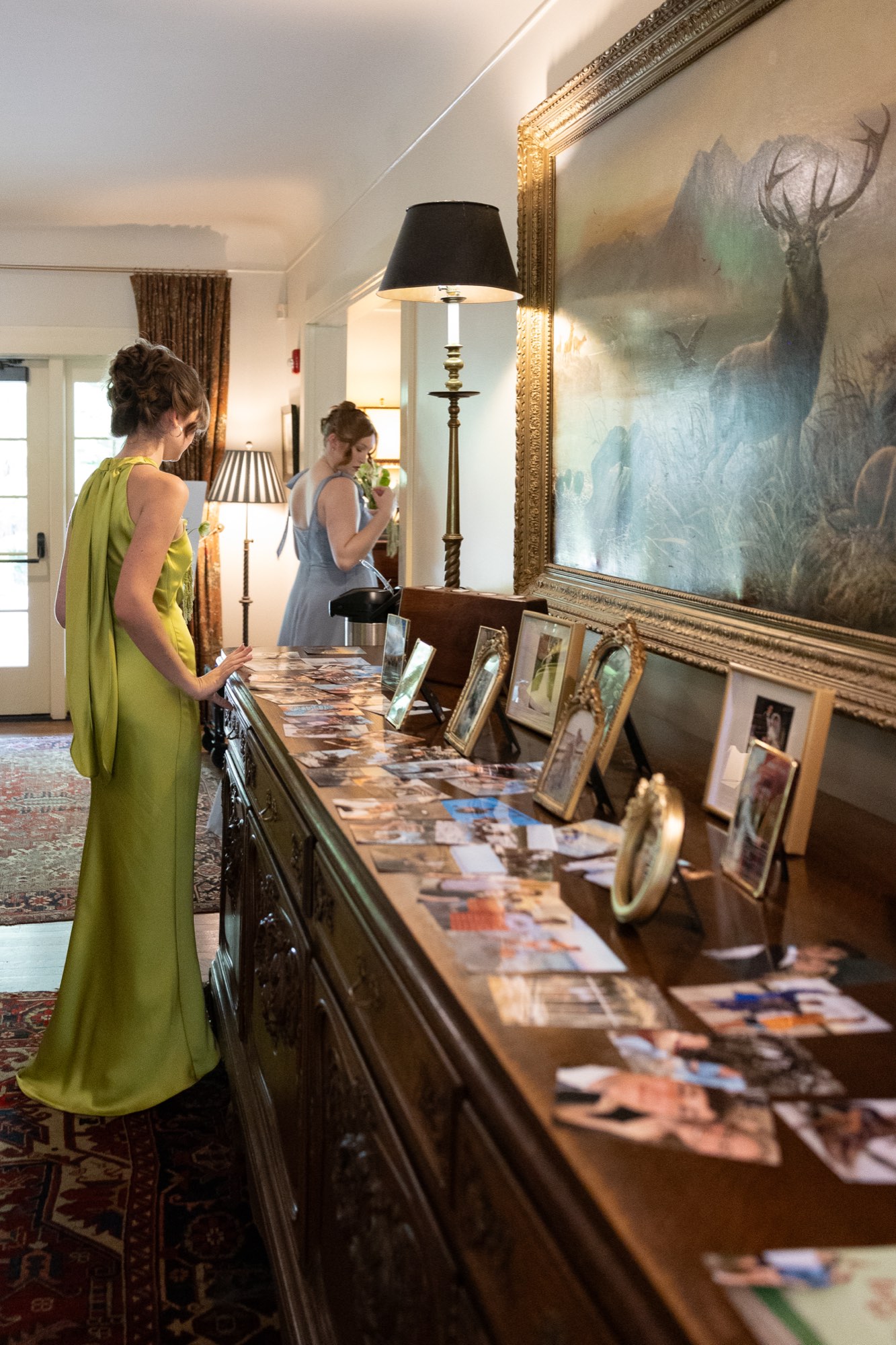 A bridesmaid in green in a hallway of framed photographs