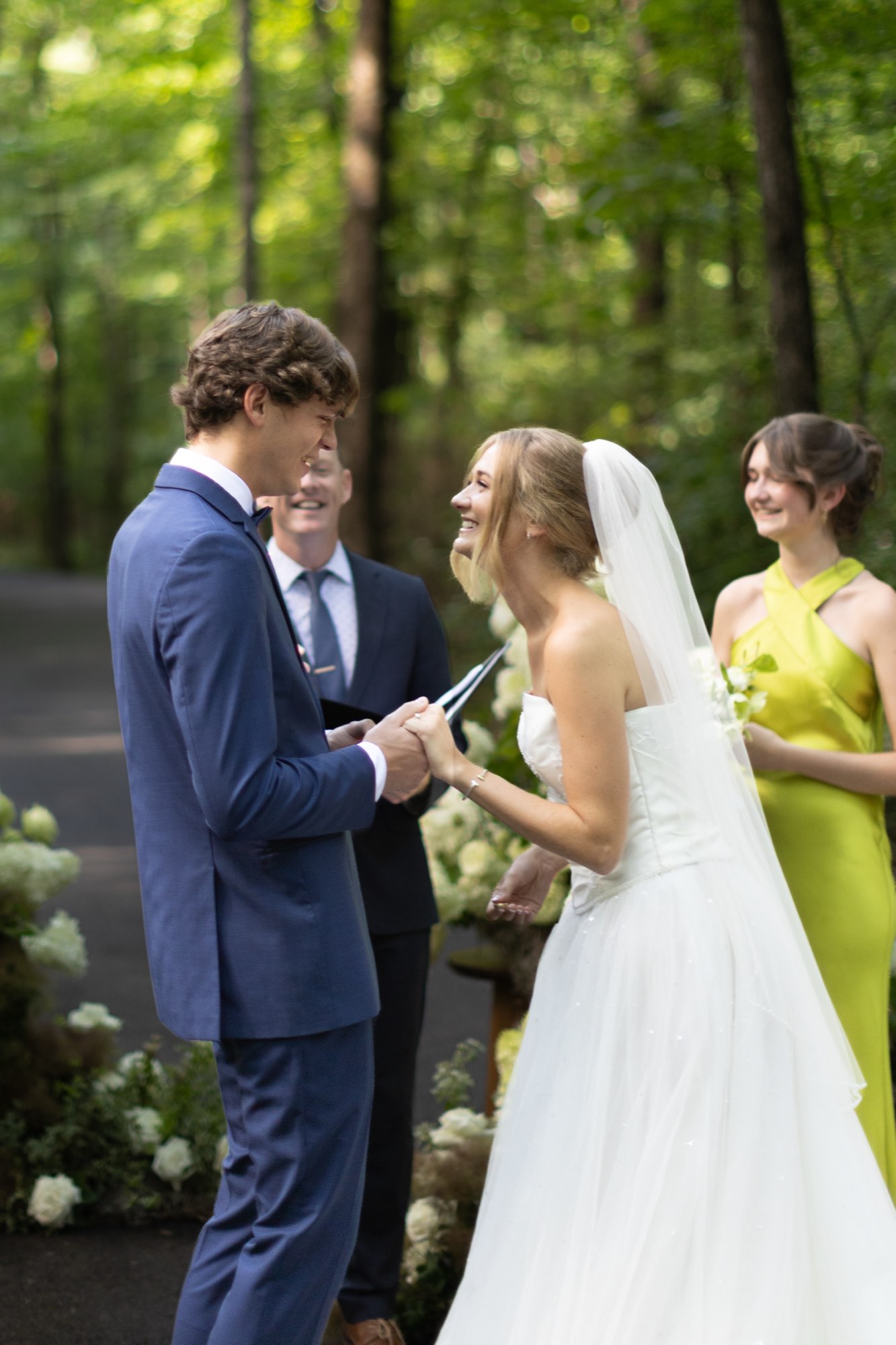 The couple laughing with a bridesmaid in green