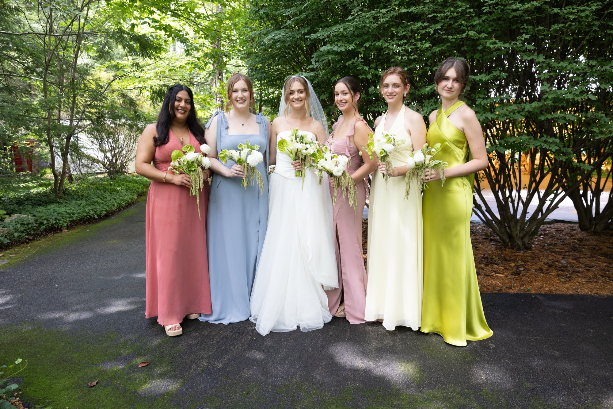 The bridesmaids in pastel dresses on the lawn