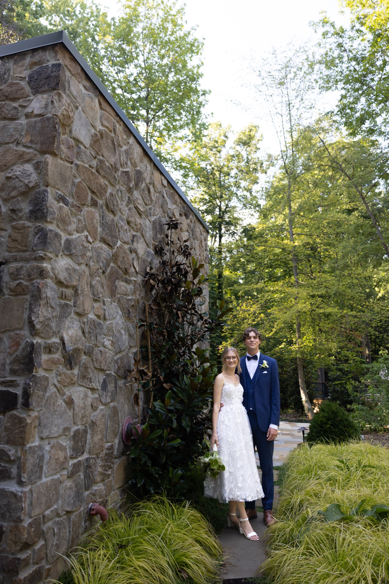 The couple small beside an old stone wall