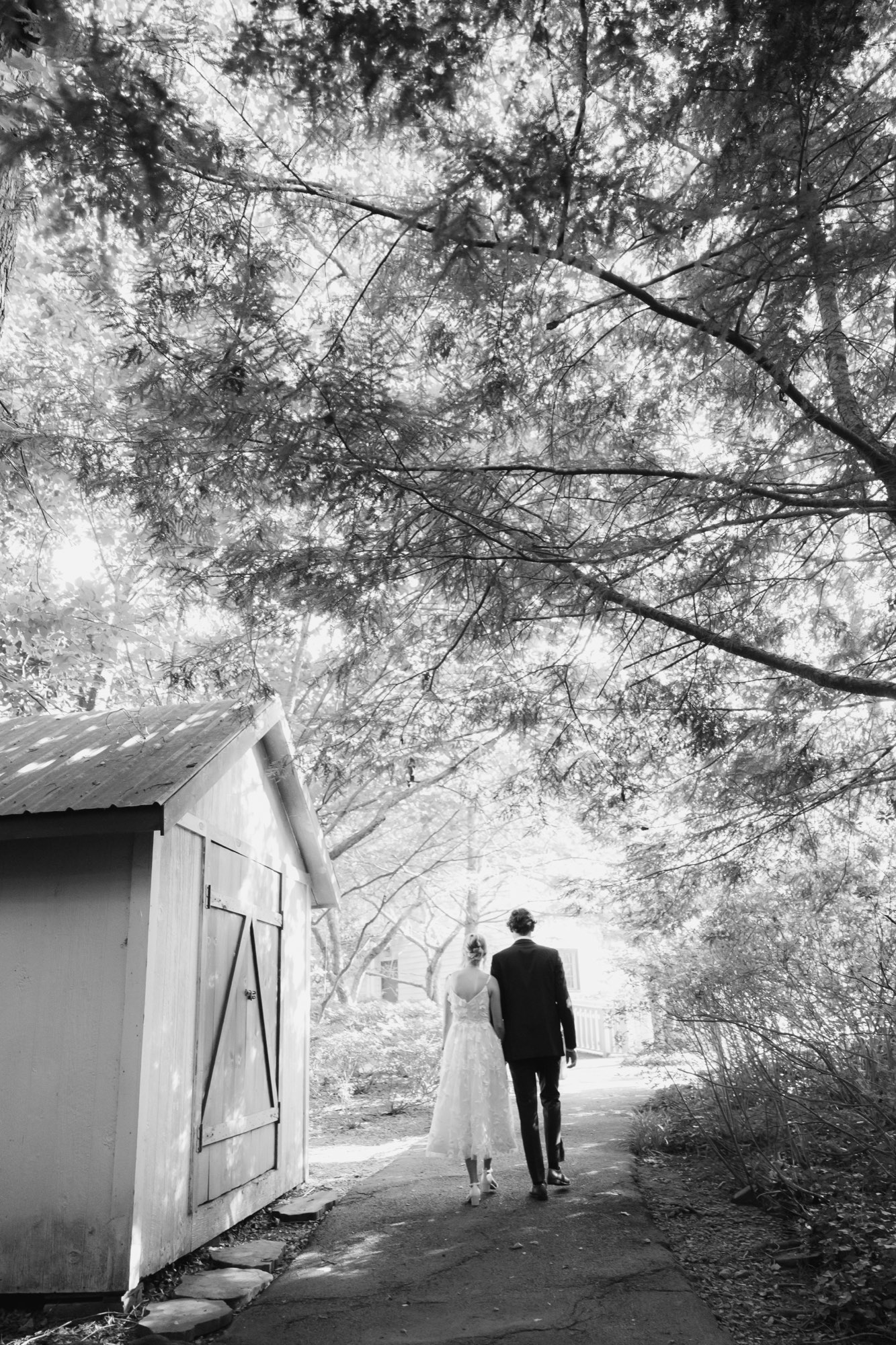 The groom walking toward a white cottage, in black and white
