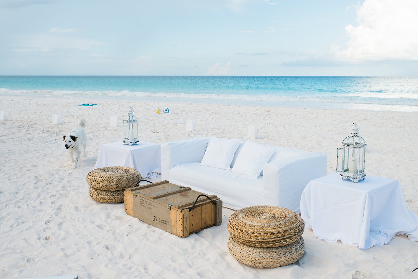 A white lounge set on the sand before guests arrive