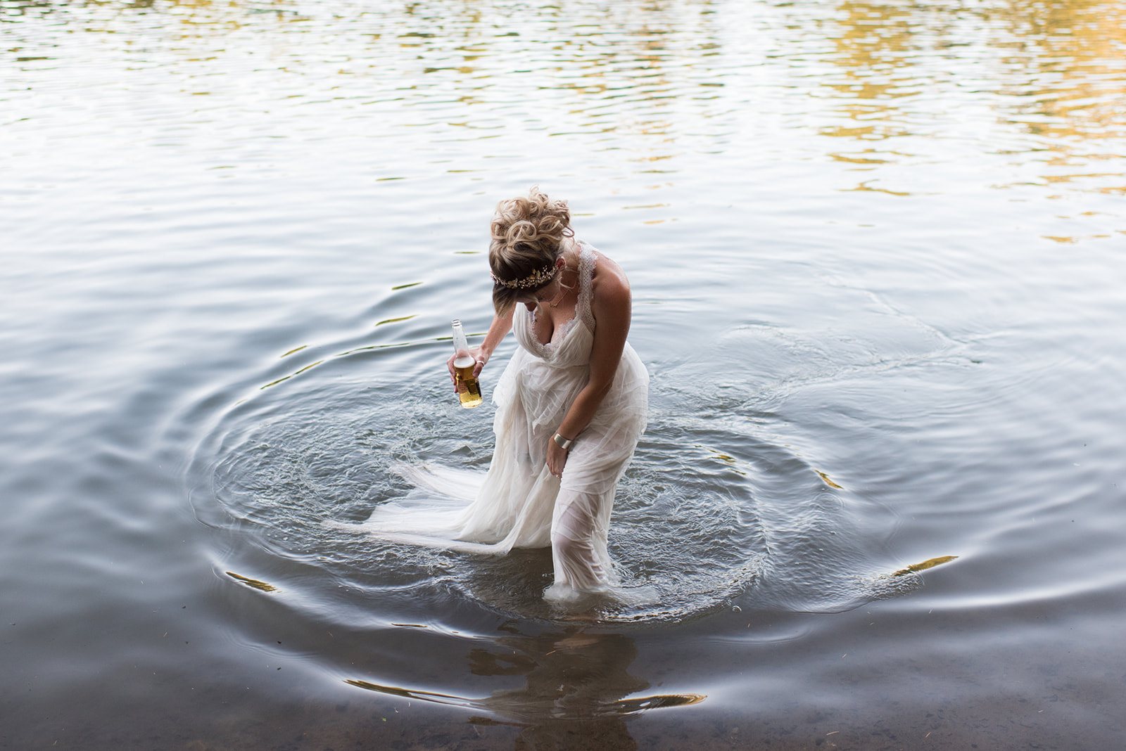 The bride wading into the lake