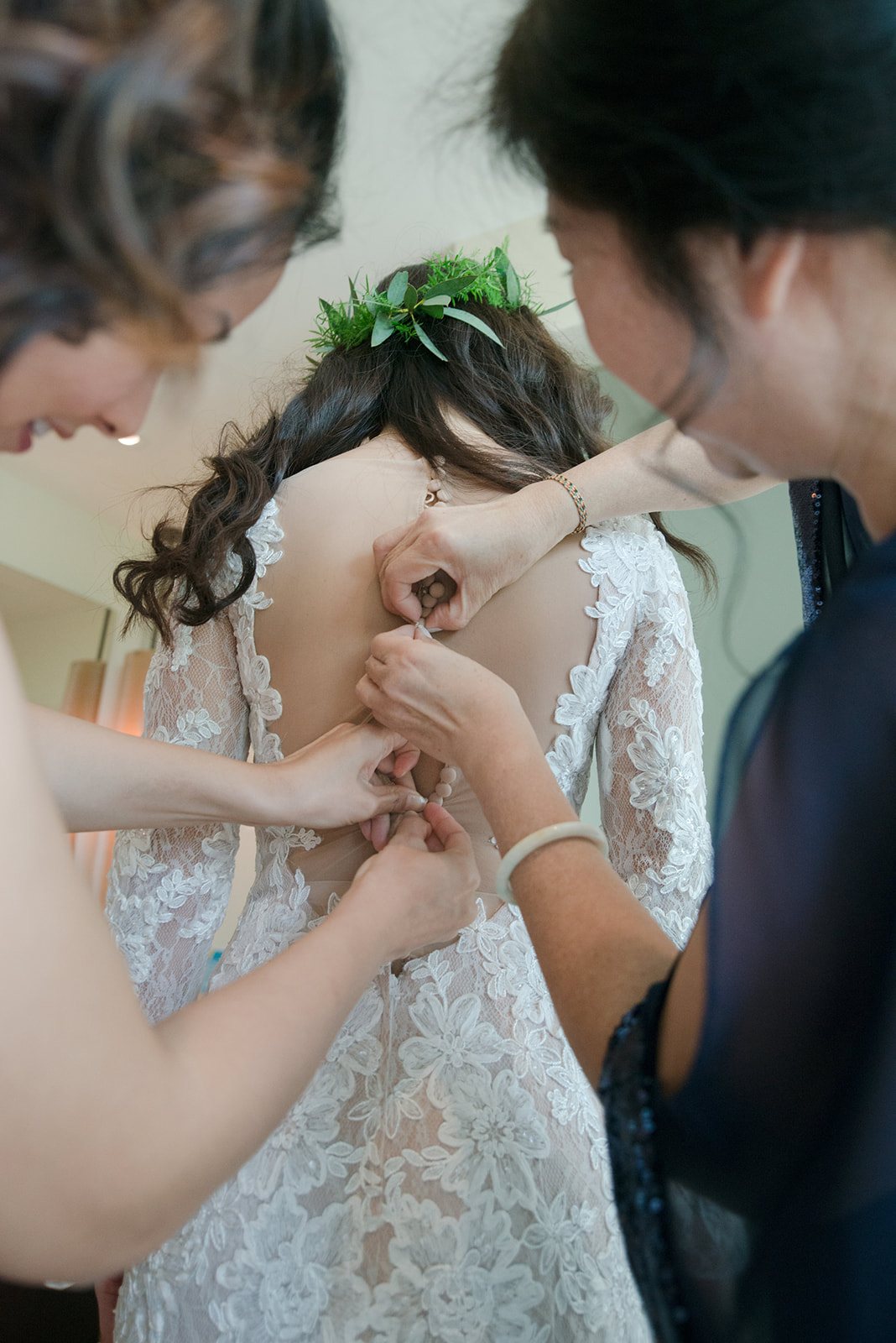 A bride being buttoned into her dress