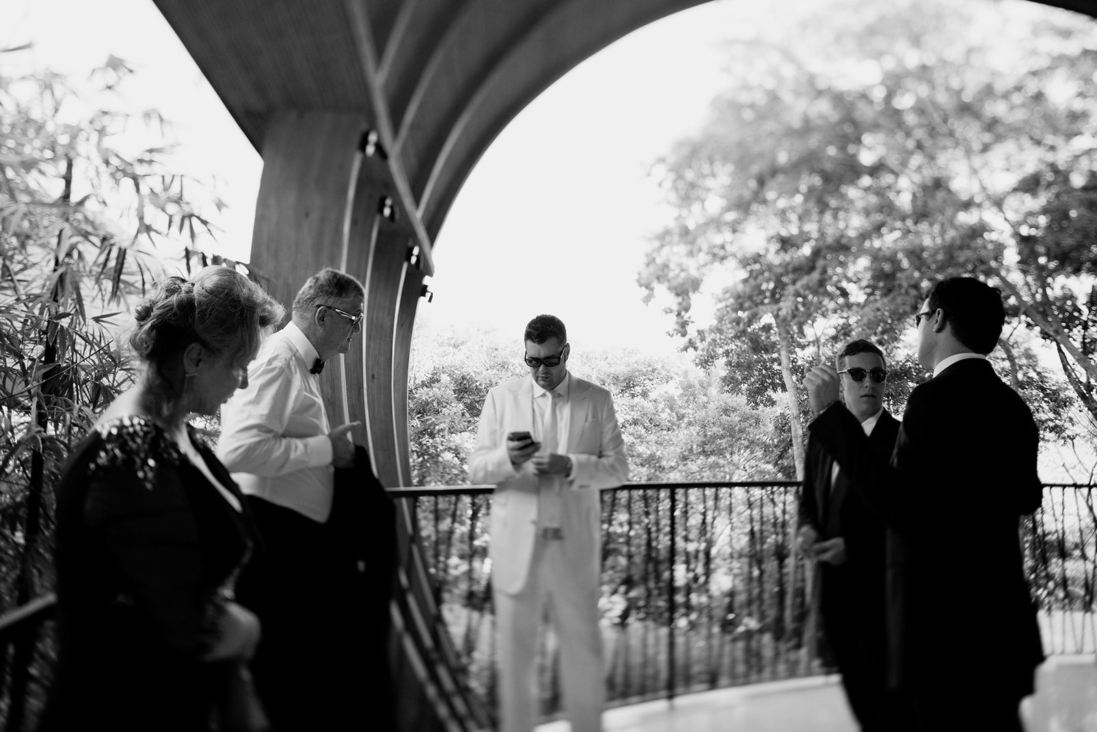 The groom and his friends under an arch in black and white