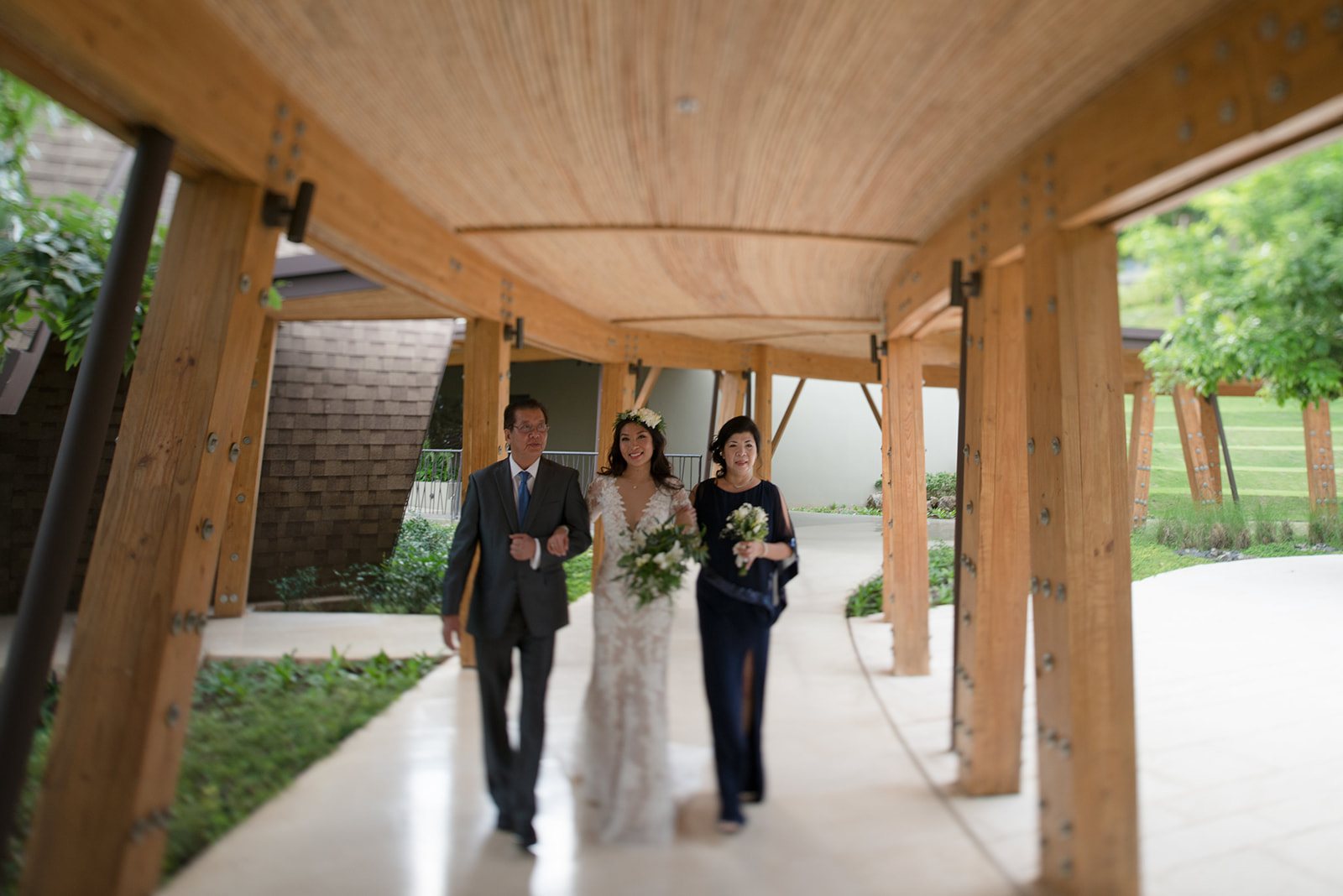 The bride and her parents under the wooden walkway