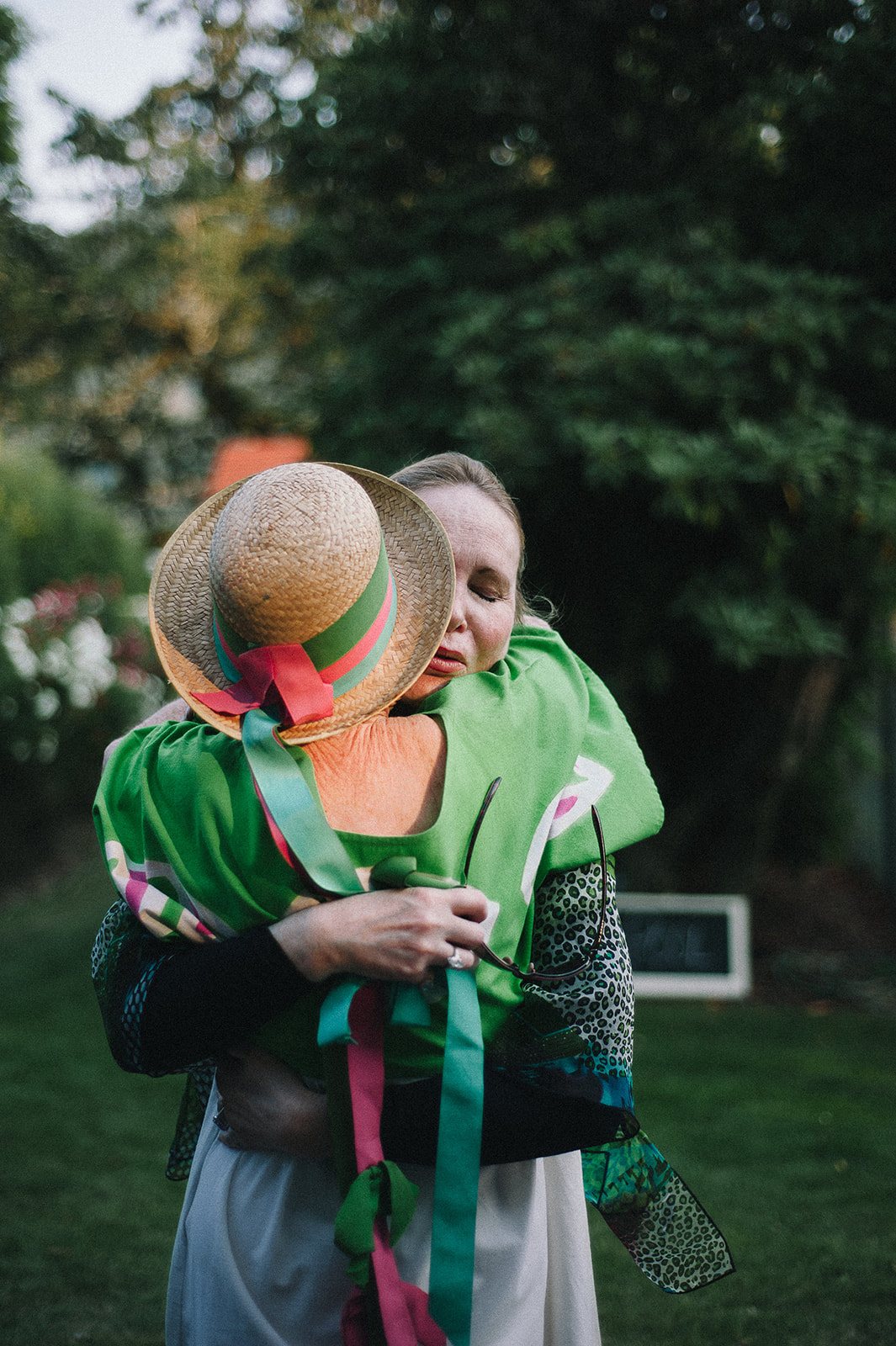 Two friends hugging, one in a green hat