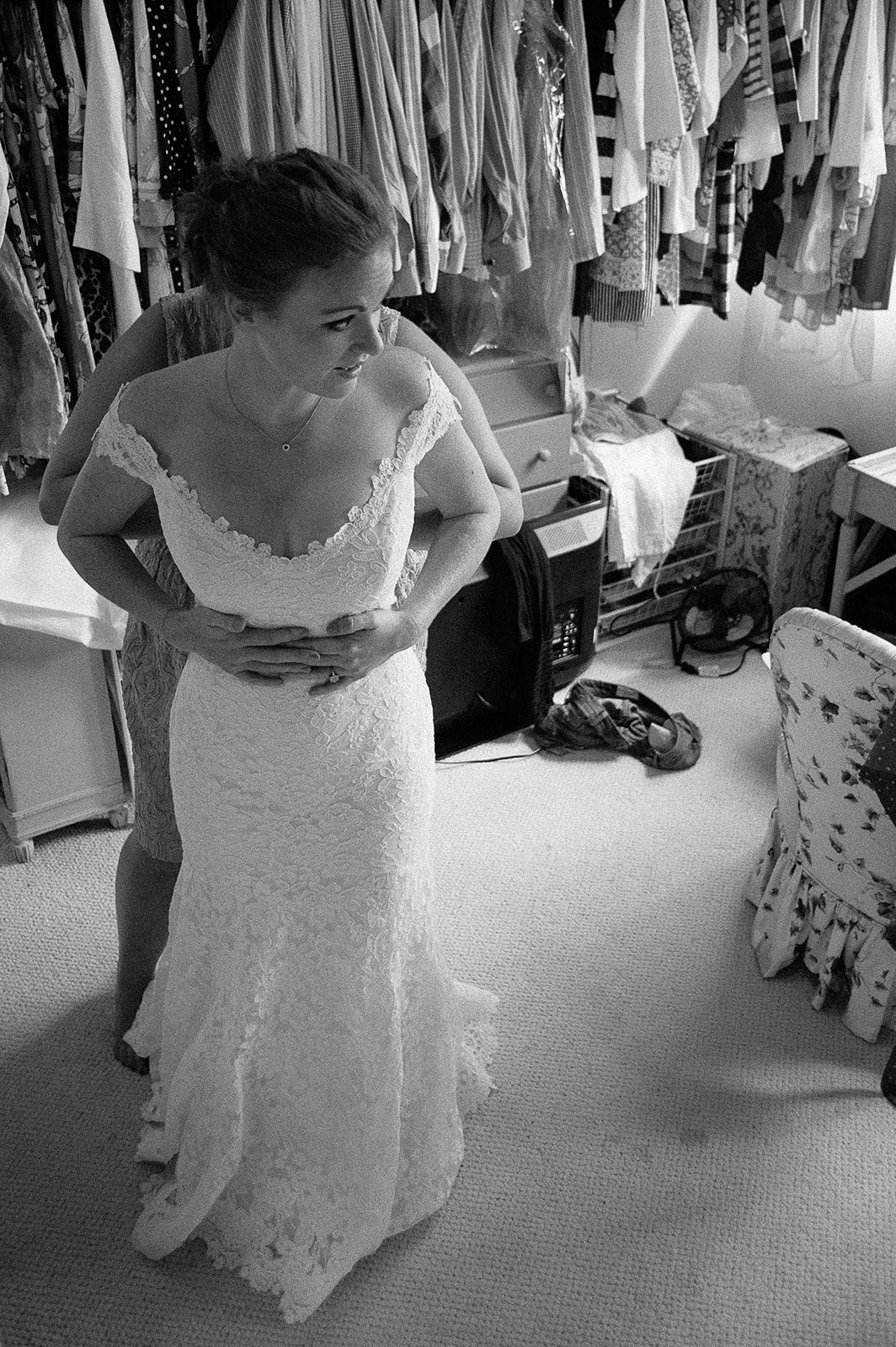 A wedding dress hanging among coats, in black and white