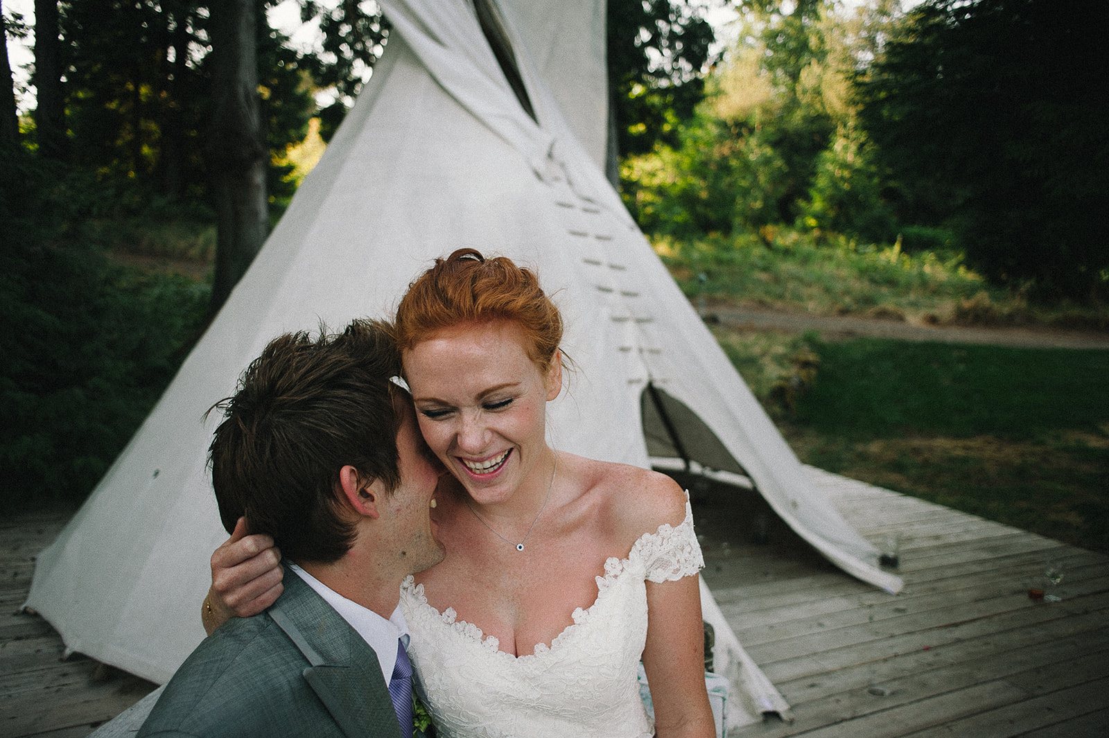 The couple laughing beside the white tipi
