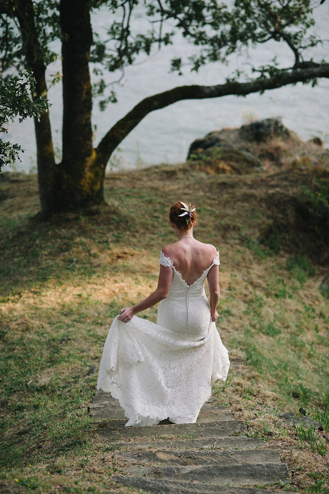 The bride walking down a stone path toward the river